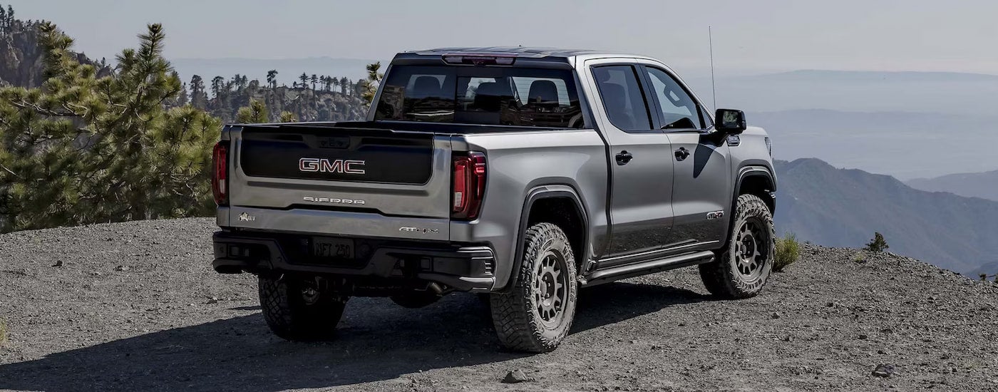 Rear view of a silver 2024 GMC Sierra 1500 AT4X parked at a mountain overlook.